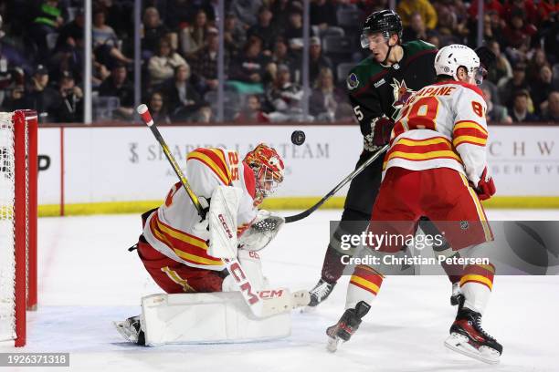 Goaltender Jacob Markstrom of the Calgary Flames makes a save as Michael Kesselring of the Arizona Coyotes looks for a rebound during the second...