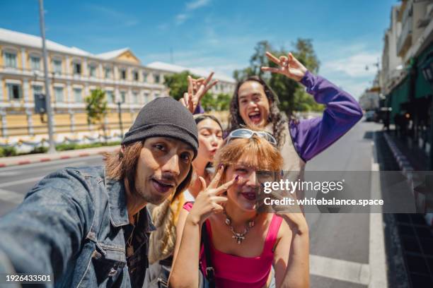 asian group friend are enjoy walking on the bangkok street and using smart phone taking a picture together - rugzaktoerist stockfoto's en -beelden