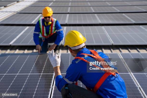 blue collar workers are checking solar panel at roof top. - ok werk stock-fotos und bilder