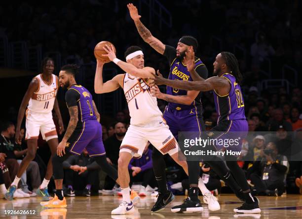 Devin Booker of the Phoenix Suns looks to pass out of a double team from Anthony Davis and Taurean Prince of the Los Angeles Lakers during the first...