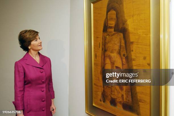 First Lady Laura Bush, looks at a photograph of one of the Bamyan Boudhas, 15 May 2002 during her visit at the Guimet museum in Paris. The museum is...