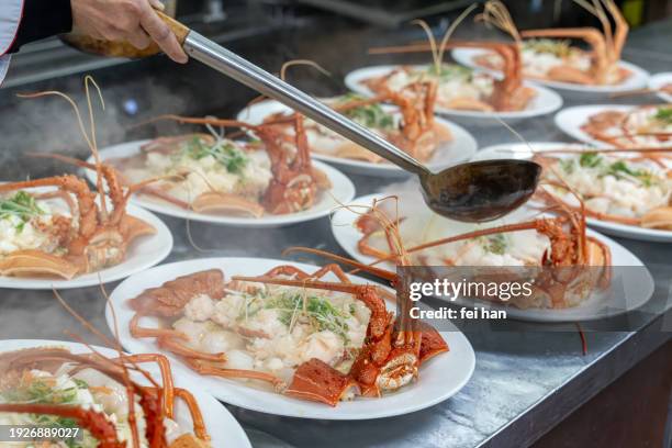 the chef's hand is operating the cooked lobster on the plate - china lobster stock pictures, royalty-free photos & images