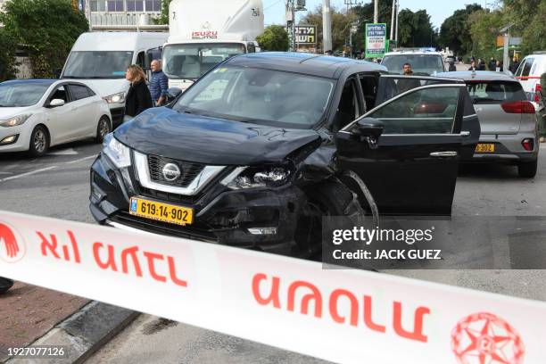 Israeli emergency and security personnel stand next to a damaged car following a suspected ramming attack in the central town of Raanana, on January...