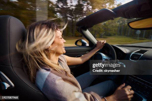 cheerful woman driving a convertible car in blurred motion. - brand name domestic car stock pictures, royalty-free photos & images