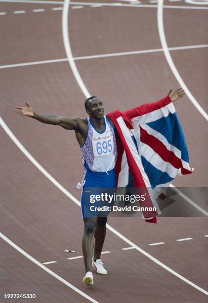 Linford Christie of Great Britain raises his arms aloft holding the Union Jack flag as he celebrates winning the the Men's 100 metres race on 1st...