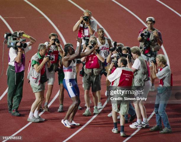 Surrounded by photographers, Linford Christie of Great Britain celebrates after winning the Men's 100 metres race at the 4th International...