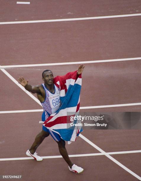 Linford Christie of Great Britain raises his arms aloft holding the Union Jack flag as he celebrates winning the the Men's 100 metres race on 1st...