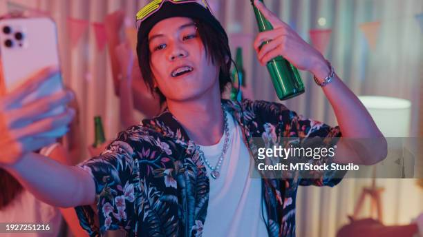 young asian man taking selfie getting drunk and dancing moving rhythmically in good mood at colorful house party at night. multicultural friends having fun together college house party. - gig living room stock pictures, royalty-free photos & images