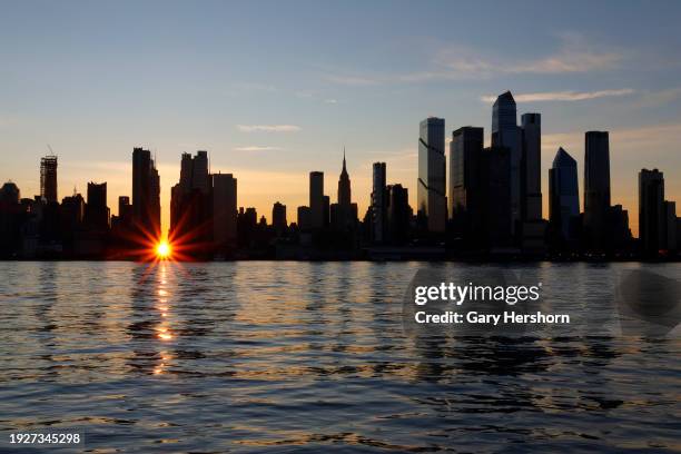 The sun rises over 42nd street behind the skyline of midtown Manhattan during a reverse Manhattanhenge sunrise in New York City on January 12 as seen...