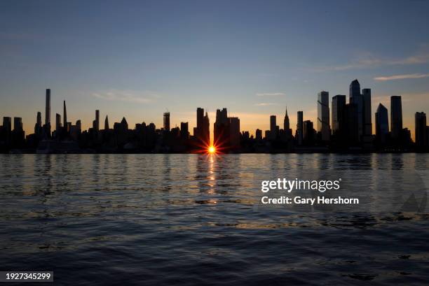 The sun rises over 42nd street behind the skyline of midtown Manhattan during a reverse Manhattanhenge sunrise in New York City on January 12 as seen...