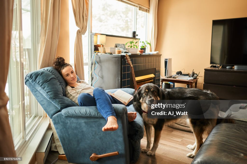 Smiling young woman and her dog relaxing at home in winter