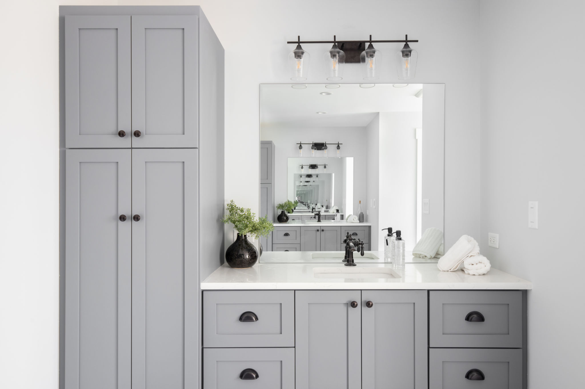 A bathroom detail with a grey cabinet and white countertop. A bathroom detail with a grey cabinet and white countertop.