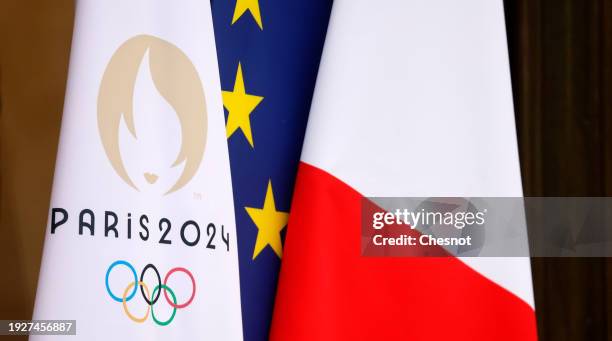 The flag of the Paris 2024 Olympic Games is seen near the French national flag and the European flag at the entrance of the Elysee Palace during the...