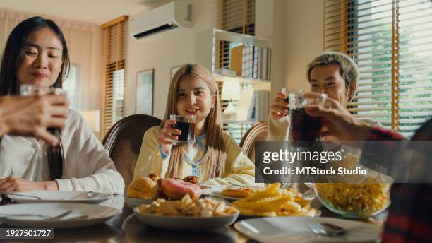 group of young asian people drinking cola and having fun sitting at dining table at home. multicultural friends having fun together college house party. - pepsi stock pictures, royalty-free photos & images