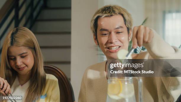 group of young asian people preparing and having fun sitting at dining table at home. multicultural friends having fun together college house party. - service of thanksgiving stock pictures, royalty-free photos & images