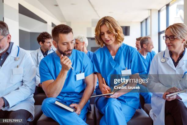 female and male nurses discussing during staff meeeting - staff meeting stock pictures, royalty-free photos & images