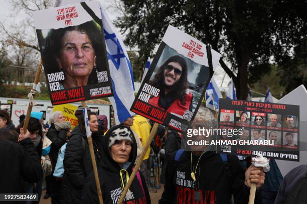 Protesters lift placards and national flags during a rally demanding the release of Israelis taken hostage a hundred days earlier by the Palestinian...