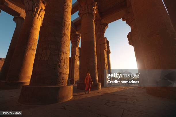 temple of kom ombo, egypt. rearview of tourist woman wear traditional dress with sunset landscape with ancient building architecture near nile river. - egito imagens e fotografias de stock