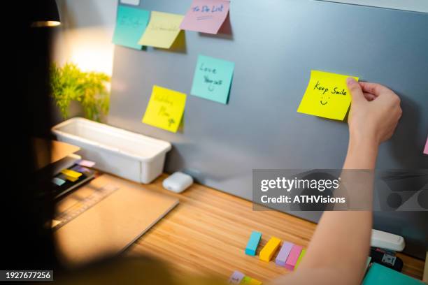 woman using post it while working at home. motivation - holding sticky note stock pictures, royalty-free photos & images