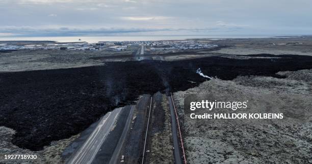 An aerial view taken on January 15, 2024 shows a lava stream across a road near Grindavik, southwest of the capital Reykjavik, after a volcanic...