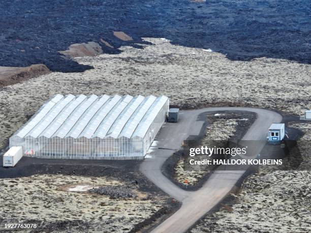 An aerial view taken on January 15, 2024 shows a lava stream near a greenhouse facility of biotechnology company ORF Genetics in Grindavik, southwest...