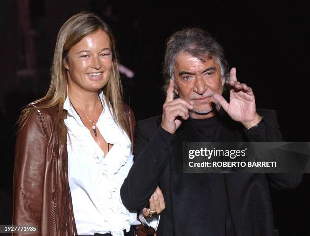 Italian designer Roberto Cavalli and his wife Eva acknowledge the applause at the end of Cavalli's Autumn/Winter 2004 men's collection at Milan...