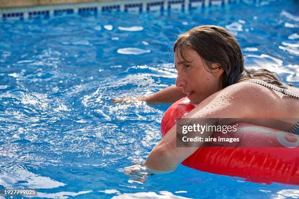 rear view of mature woman relaxed at swimming pool resting on inflatable ring - denia stock pictures, royalty-free photos & images