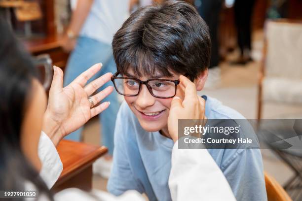 10代��の少年は、眼鏡店のオフィスで新しい眼鏡をかけています - asian child with new glasses ストックフォトと画像