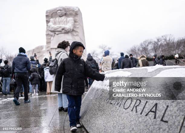 Boy plays with snow at the Martin Luther King Jr. Memorial, after the start of a wreath-laying ceremony honoring the legacy of the late civil rights...