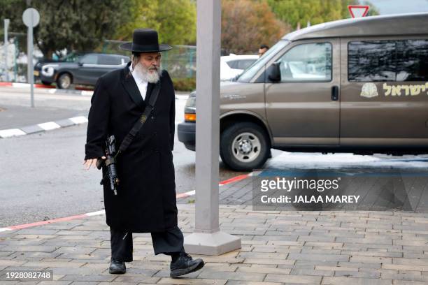 An ultra-Orthodox Jewish man carries a weapon as he arrives for the funeral of an Israeli mother and son killed after a missile fired from Lebanon...