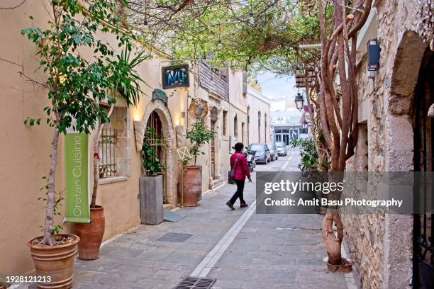 a woman tourist is seen walking  the narrow streets of old town rethymnon, crete - rethymnon town stock-fotos und bilder
