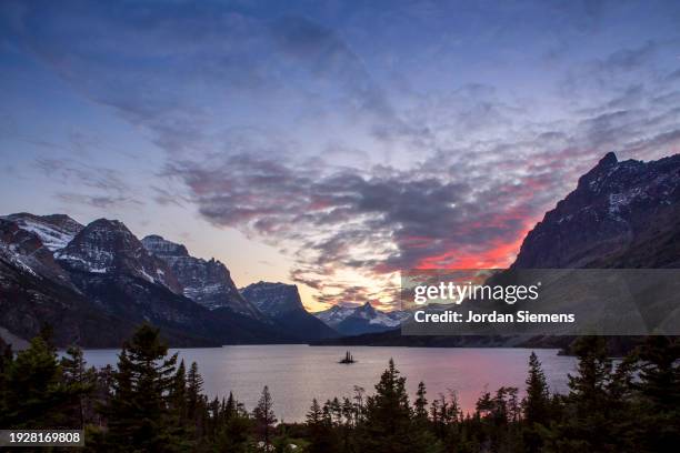 a dramatic sunset over wild goose island in glacier national park. - lake whitefish stock-fotos und bilder