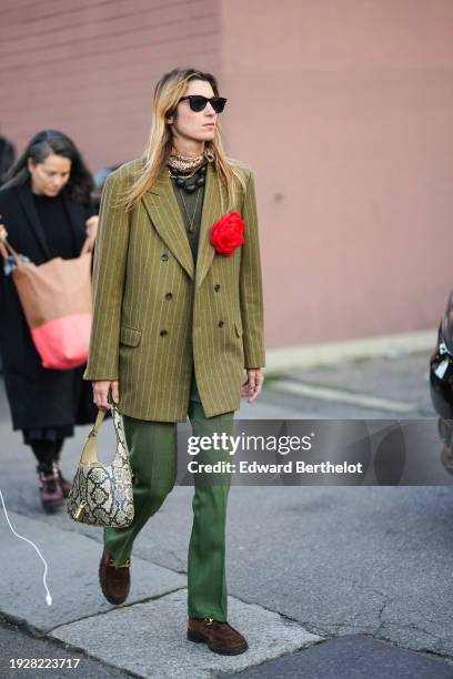 Guest wears sunglasses, a green striped oversized blazer jacket, a pearl necklace, green suit pants, a snake print Gucci bag, brown suede shoes,...