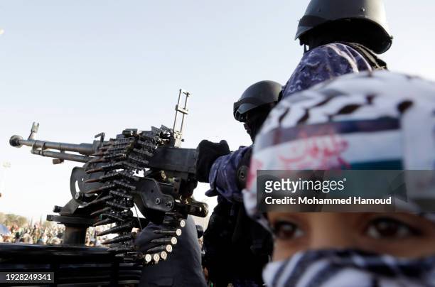Child wearing a headband with the words 'Al-Aqsa storm stands next to security soldiers who guard during a protest staged against violating Yemen's...