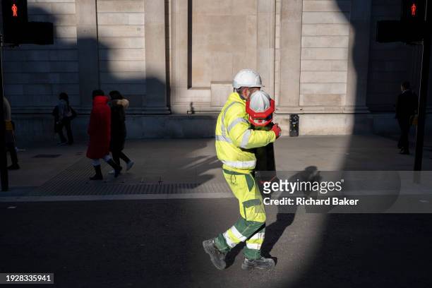 Workman with streets contractor Conway carries a heavy bollard through winter sunlight beneath the tall walls of the Bank of England on Threadneedle...