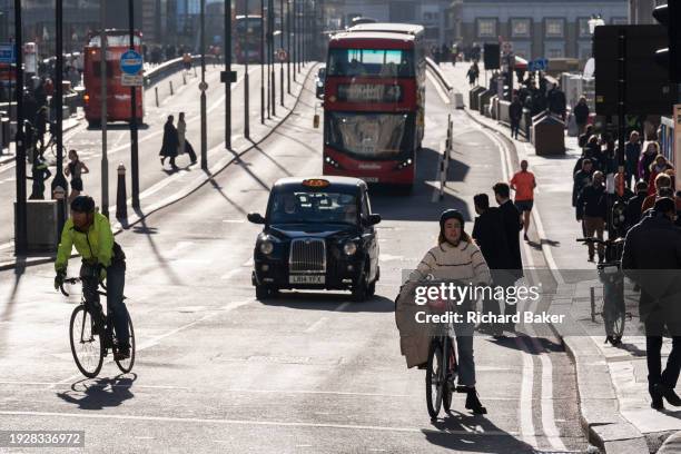 Cyclists pause at traffic lights in front of a taxi cab and bus on London Bridge in the City of London, the capital's financial district, on 15th...