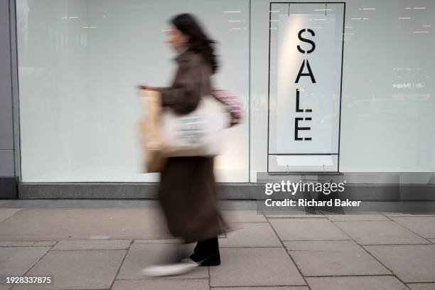 Shopper blurs past a generic shop business whose January Sales are now on, on Victoria Street in Westminster, on 12th January 2024, in London,...