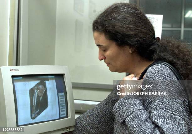 Lebanese Umaya Abboud , looks on an AFP monitor in Beirut 18 March 2000, at a picture of her husband Masao Adachi escorted by police upon his arrival...