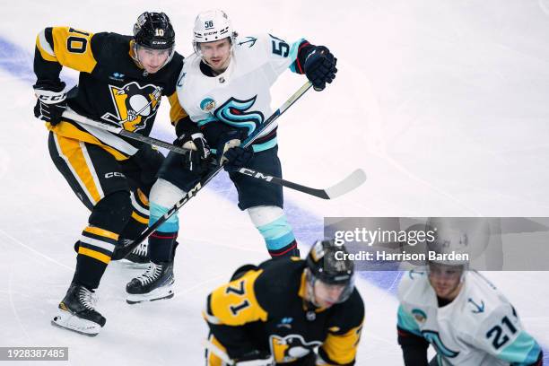 Drew O'Connor of the Pittsburgh Penguins and Kailer Yamamoto of the Seattle Kraken defend each other during a face off during the third period at PPG...