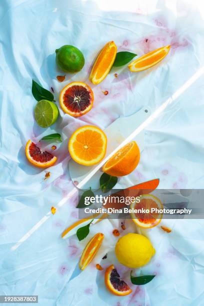 citrus fruits cut with a ray of light on a white tablecloth, sun knife concept - orange peel texture stock pictures, royalty-free photos & images