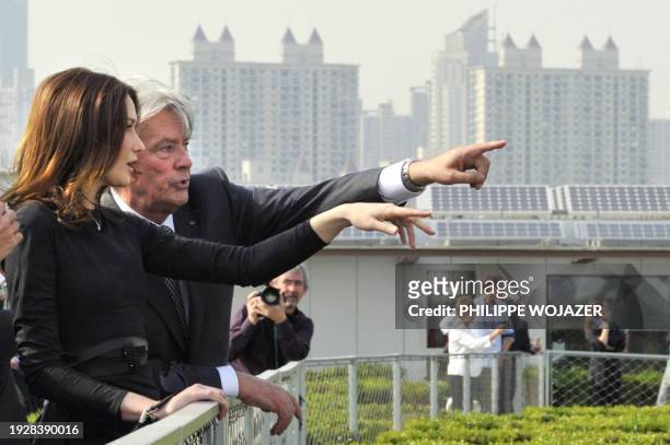 France's President Nicolas Sarkozy's wife Carla Bruni-Sarkozy and French actor Alain Delon gestures as they walk in the French pavilion, during a...
