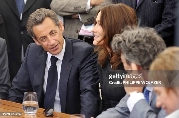 France's President Nicolas Sarkozy , his wife Carla Bruni-Sarkozy and French Ecology Minister Jean-Louis Borloo sit at a terrace table as they visit...