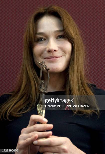 France's first Lady Carla Bruni-Sarkozy holds a statue of a woman and child offered to her at an AIDS Global fund meeting in Ouagadougou on February...
