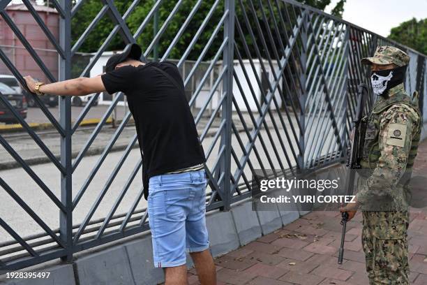 Navy soldier guards a man suspected of belonging to a criminal gang during a joint operation between the Ecuadorean National Police and members of...