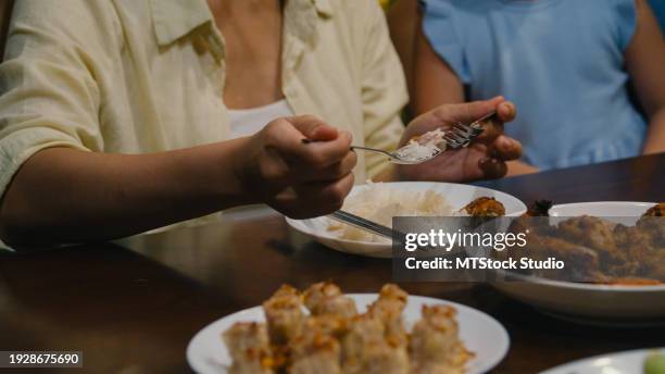 closeup of asian family eating chinese food and having fun dinner sitting at dining table at backyard outside home at night. multi-generation family enjoying spending together. - chinese eating backyard ストックフォトと画像