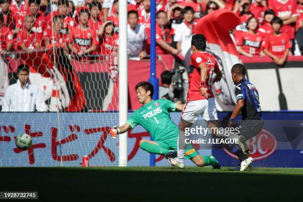 Ademilson of Gamba Osaka scores the team's first goal past Shusaku Nishikawa of Urawa Red Diamondsduring the J.League YBC Levain Cup final between...