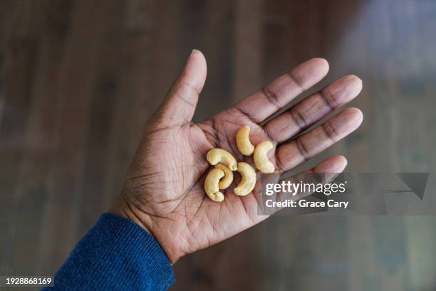 woman holds a handful of cashews - cashew pieces stock pictures, royalty-free photos & images