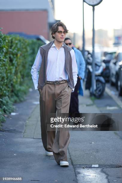 Guest wears sunglasses, a pullover, a shirt, a Gucci belt, brown slack suit pants, sneakers shoes, outside Gucci, during the Milan Fashion Week -...