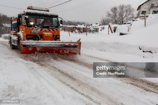 Snow plow drives uphill as thick snow covers countryside, driving conditions are very difficult and temperatures get below 0 Celsius in Krakow,...
