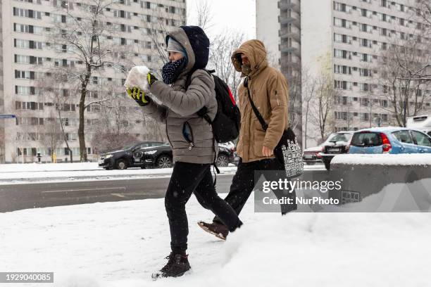 Boy holds a snow ball as thick snow fell, driving conditions get very difficult and cars are covered with fresh snow as temperatures get below 0...